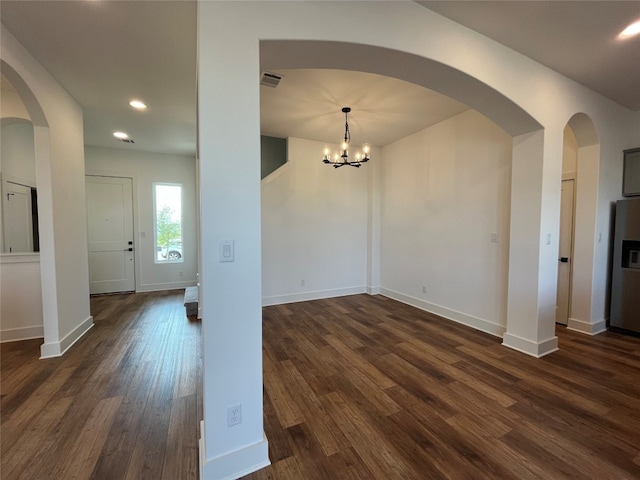 spare room with dark hardwood / wood-style floors and a notable chandelier