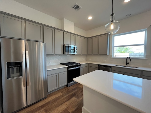 kitchen featuring sink, tasteful backsplash, gray cabinets, stainless steel appliances, and dark hardwood / wood-style flooring