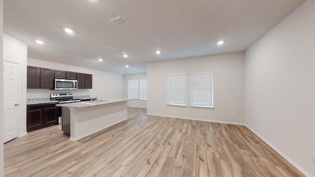 kitchen with dark brown cabinets, an island with sink, light wood-type flooring, and sink