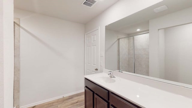 bathroom with a shower with shower door, hardwood / wood-style flooring, and vanity