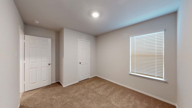 unfurnished bedroom with light carpet and a closet