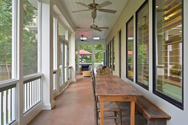 unfurnished sunroom with ceiling fan, wood ceiling, and a wealth of natural light