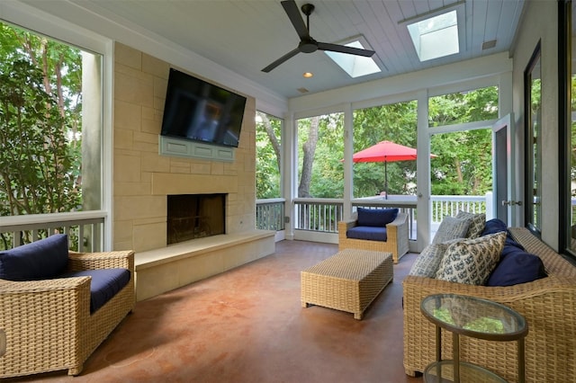 sunroom / solarium featuring ceiling fan, a skylight, a fireplace, and a healthy amount of sunlight