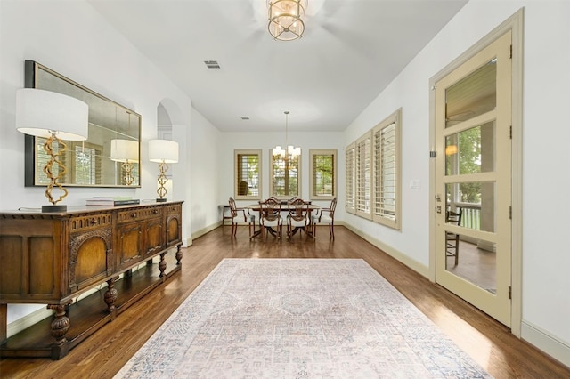 dining area with baseboards, visible vents, a chandelier, and wood finished floors