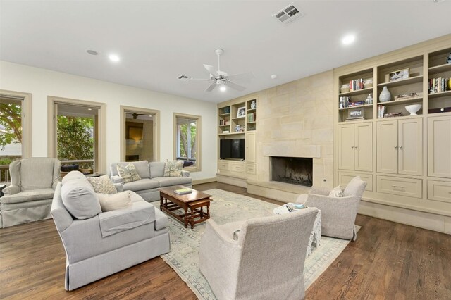 living room featuring a healthy amount of sunlight, dark wood-type flooring, ceiling fan, and a fireplace