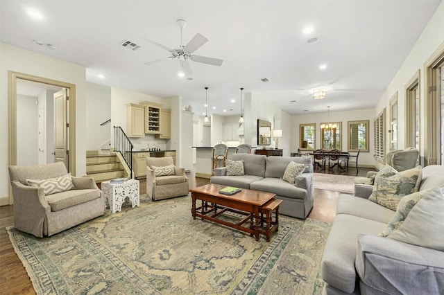 living room with recessed lighting, ceiling fan with notable chandelier, visible vents, wood finished floors, and stairs