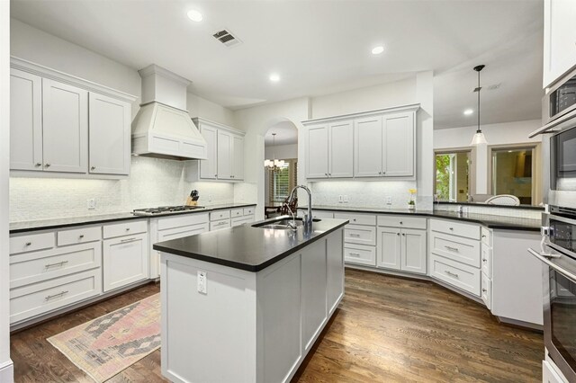 kitchen with white cabinets, custom exhaust hood, decorative light fixtures, and sink