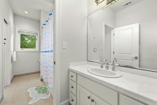 bathroom featuring baseboards, vanity, visible vents, and tile patterned floors