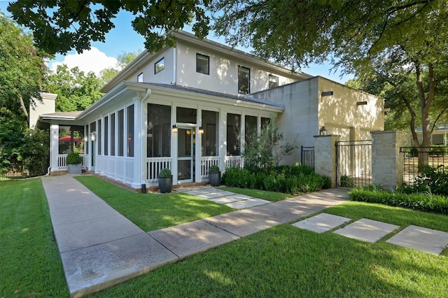 view of front of house with fence, a sunroom, a gate, stucco siding, and a front lawn