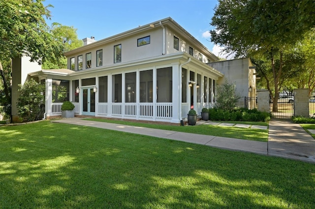 view of front facade with a sunroom, french doors, stucco siding, a chimney, and a front yard