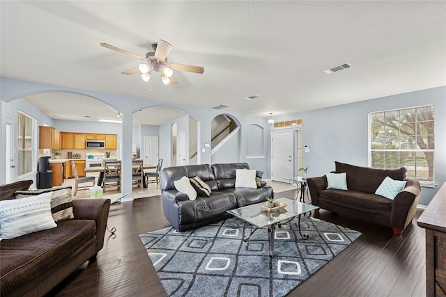 living room with ceiling fan and dark hardwood / wood-style flooring