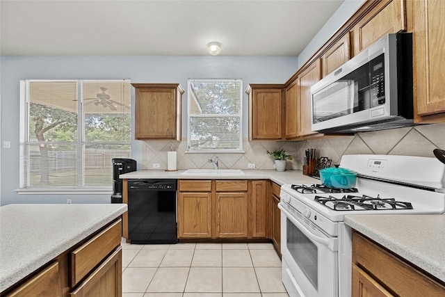 kitchen featuring dishwasher, white gas stove, light tile patterned flooring, sink, and backsplash