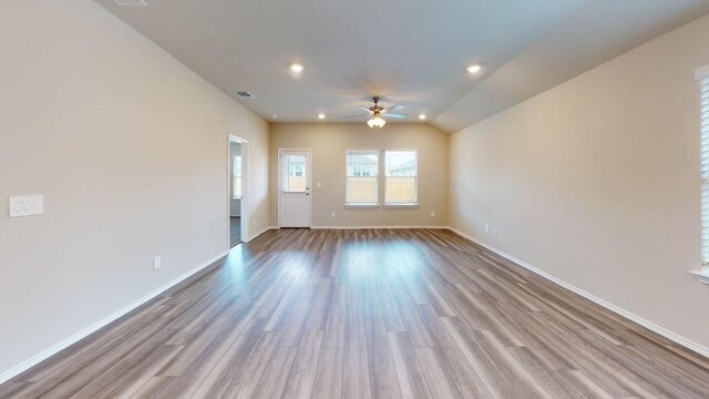 empty room with light hardwood / wood-style flooring, lofted ceiling, and ceiling fan