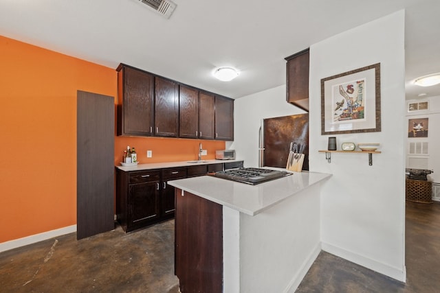 kitchen with sink, refrigerator, dark brown cabinets, stainless steel gas cooktop, and kitchen peninsula