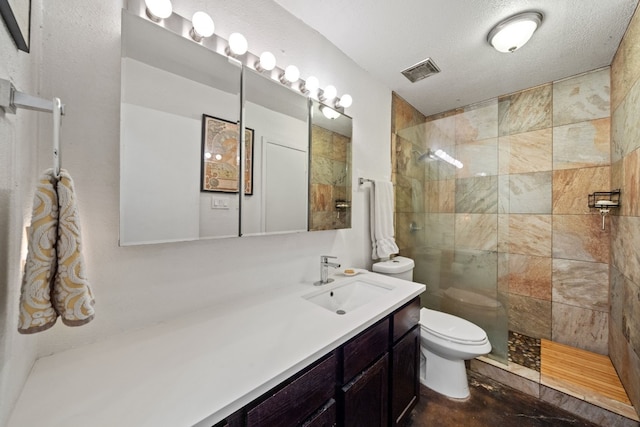 bathroom featuring vanity, a textured ceiling, toilet, and tiled shower