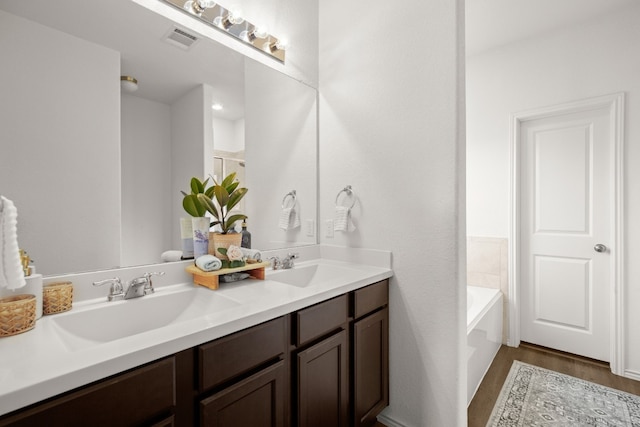 bathroom with vanity, hardwood / wood-style flooring, and a washtub