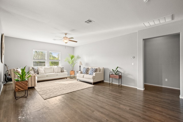 living room featuring ceiling fan, a textured ceiling, and dark wood-type flooring