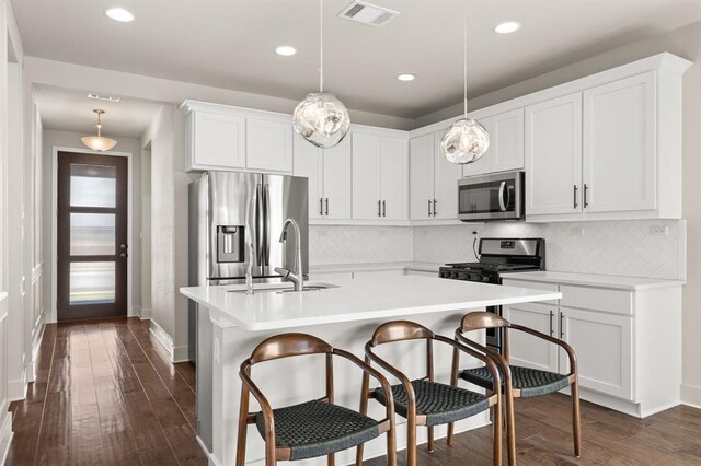 kitchen with appliances with stainless steel finishes, hanging light fixtures, dark hardwood / wood-style floors, and white cabinetry