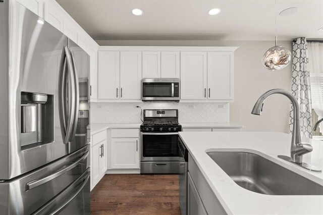 kitchen with pendant lighting, sink, white cabinetry, appliances with stainless steel finishes, and dark hardwood / wood-style flooring