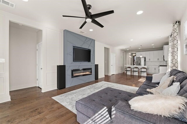 living room with ceiling fan, a fireplace, and dark hardwood / wood-style flooring