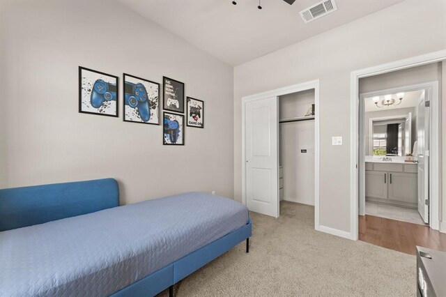 carpeted bedroom with ensuite bath, a closet, and ceiling fan