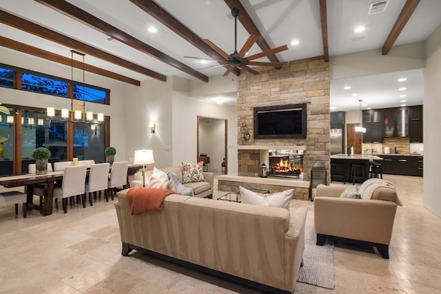 living room featuring ceiling fan, beamed ceiling, and a fireplace