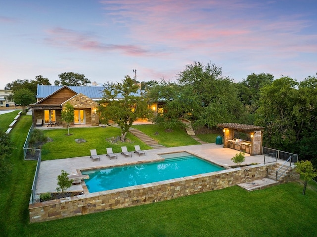 pool at dusk with a lawn and a patio