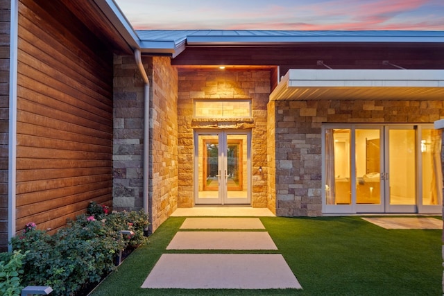 exterior entry at dusk featuring french doors and a yard