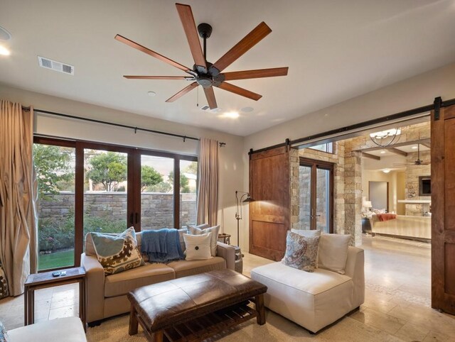 living room with ceiling fan and a barn door