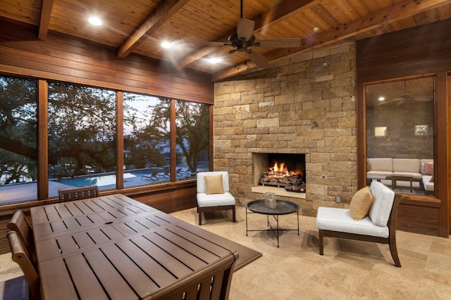 exterior space featuring beam ceiling, ceiling fan, wooden ceiling, and a fireplace