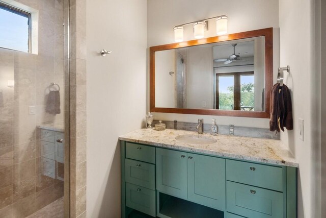 bathroom featuring a shower with door, vanity, ceiling fan, and a wealth of natural light