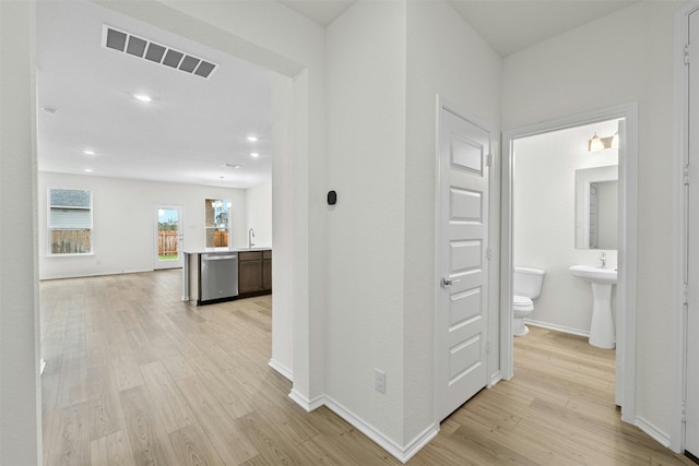 corridor featuring sink, light hardwood / wood-style flooring, and a notable chandelier