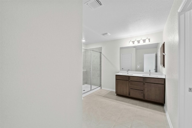 bathroom with a shower with door, vanity, a textured ceiling, and tile patterned floors