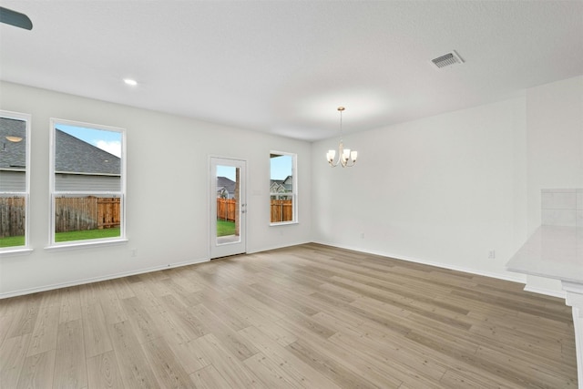 spare room with light hardwood / wood-style floors and a chandelier