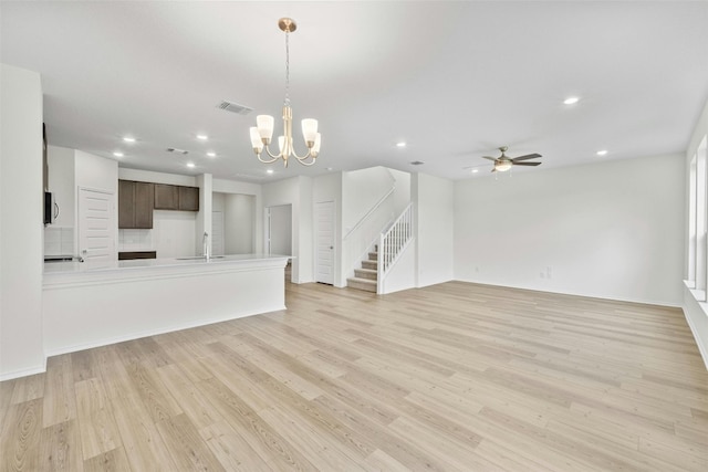 unfurnished living room with sink, light hardwood / wood-style flooring, and ceiling fan with notable chandelier