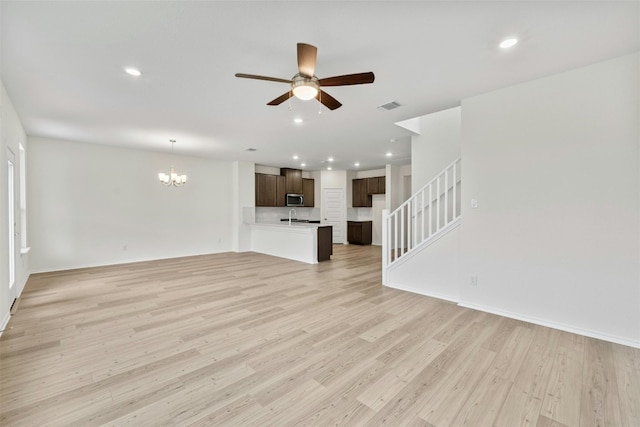 unfurnished living room with sink, ceiling fan with notable chandelier, and light hardwood / wood-style floors