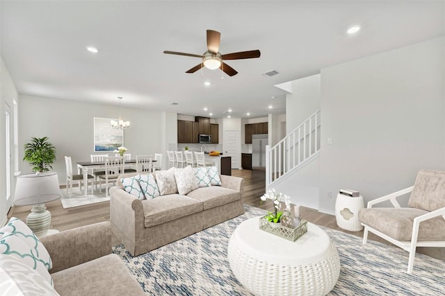 1721 Tin Can Trl, Georgetown, TX 78628 - living room featuring light wood-style floors, ceiling fan, stairs, a chandelier, and recessed lighting