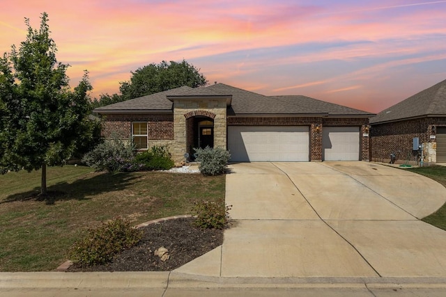 view of front of property with a garage, brick siding, driveway, and a lawn