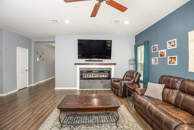 living area featuring a ceiling fan, a tiled fireplace, wood finished floors, and visible vents