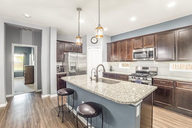 kitchen featuring tasteful backsplash, light stone countertops, stainless steel appliances, and a sink