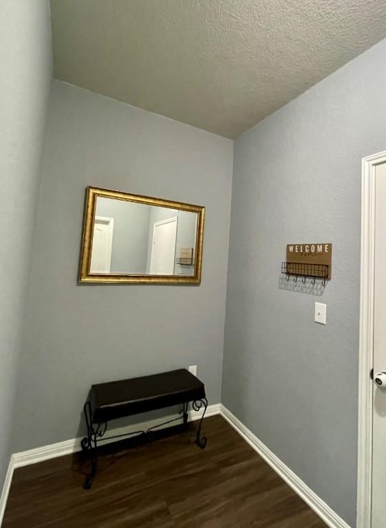 empty room featuring wood finished floors, baseboards, and a textured ceiling