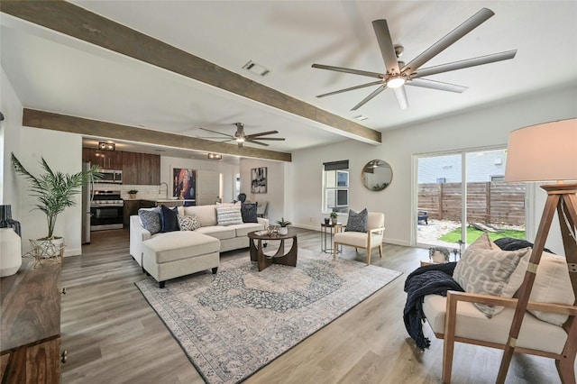 living room featuring beamed ceiling, wood-type flooring, and ceiling fan