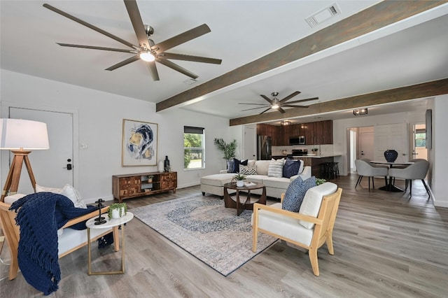 living room featuring light hardwood / wood-style flooring, beamed ceiling, and ceiling fan