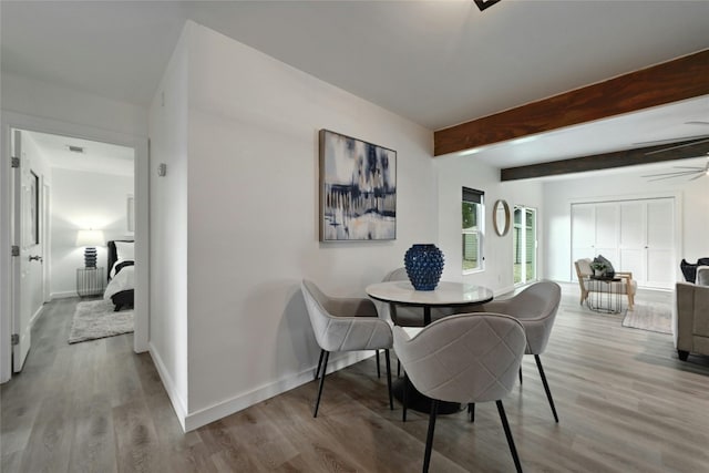 dining room with beamed ceiling, ceiling fan, and light hardwood / wood-style flooring