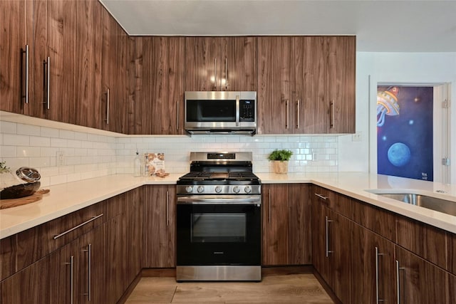 kitchen with appliances with stainless steel finishes, tasteful backsplash, and light hardwood / wood-style flooring