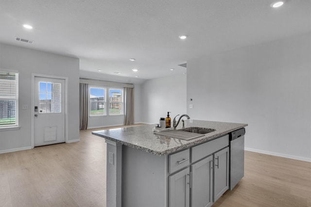 kitchen featuring sink, a center island with sink, dishwasher, and light hardwood / wood-style floors