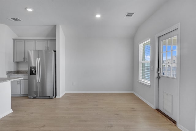 kitchen featuring lofted ceiling, gray cabinetry, light hardwood / wood-style floors, and stainless steel fridge with ice dispenser