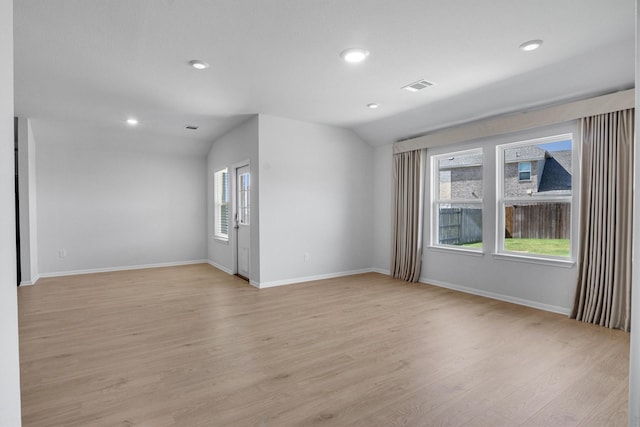 spare room with lofted ceiling and light hardwood / wood-style flooring