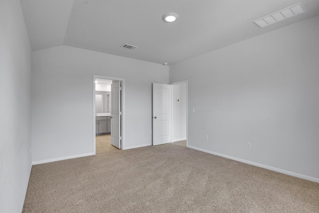 unfurnished bedroom with lofted ceiling, light carpet, and connected bathroom