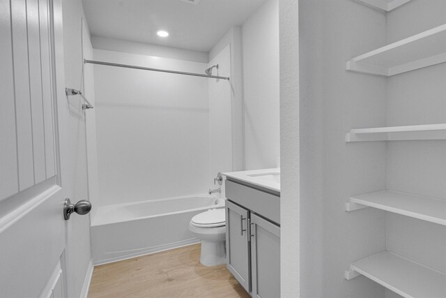 full bathroom featuring toilet, vanity, hardwood / wood-style flooring, and washtub / shower combination